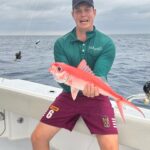 Liam holding a his freshly caught fish,.