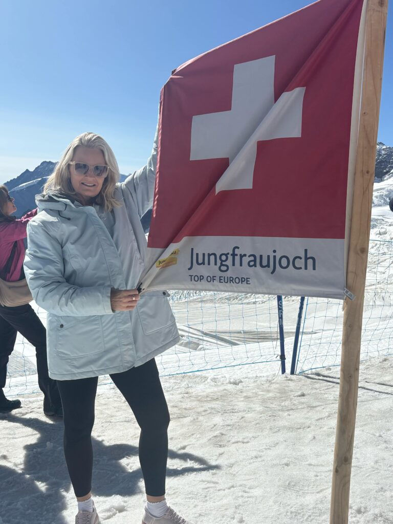 Belinda on the snowy mountains holding the Swiss flag