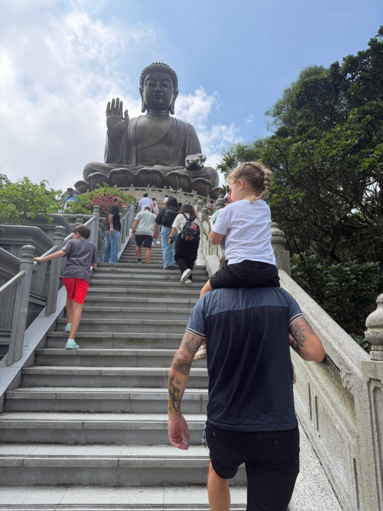 Brit's husband carrying their daughter to the Buddha statue
