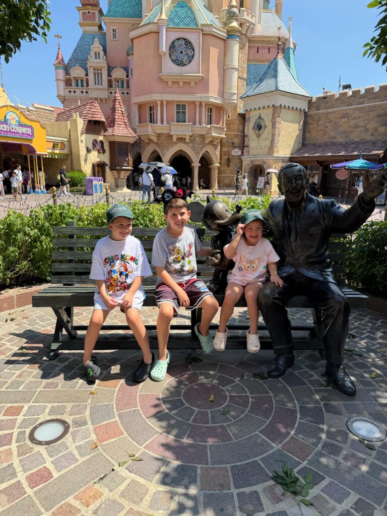 Brit's children with the Walt Disney statue on a bench